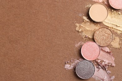 Photo of Beautiful eyeshadow refill pans on brown background, flat lay. Space for text