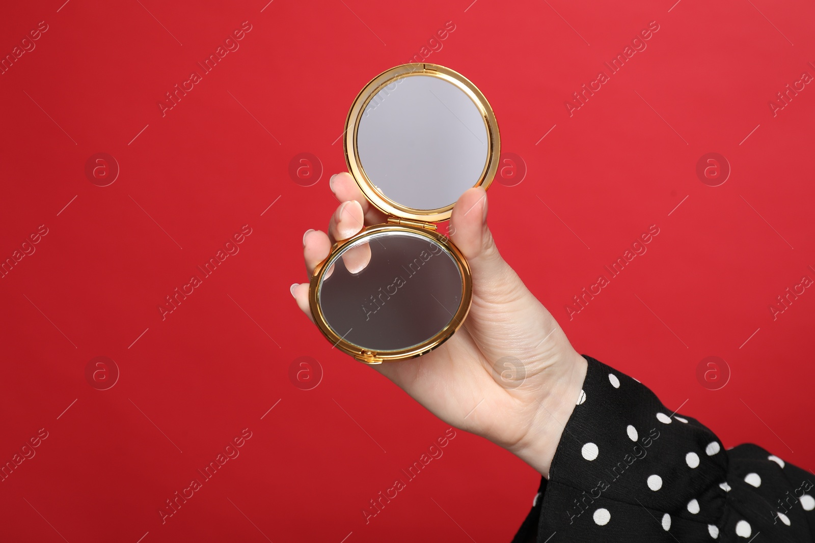 Woman holding open pocket mirror on red background, closeup Photo of Woman holding open pocket mirror on red background, closeup