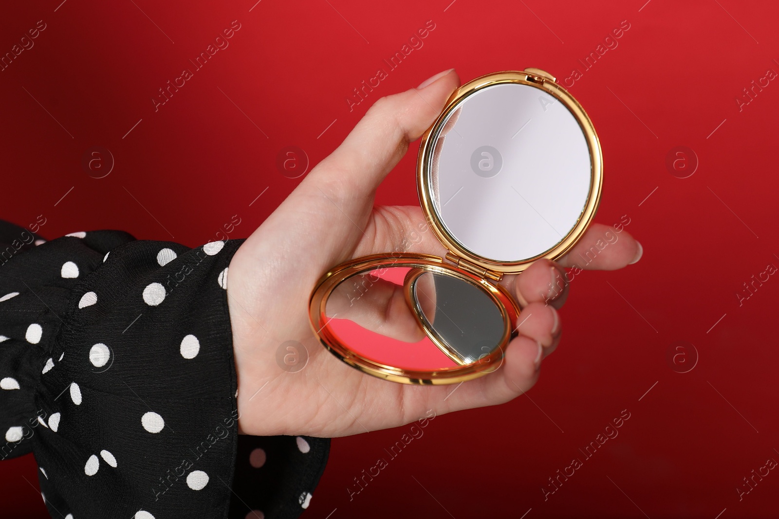 Woman holding open pocket mirror on red background, closeup Photo of Woman holding open pocket mirror on red background, closeup