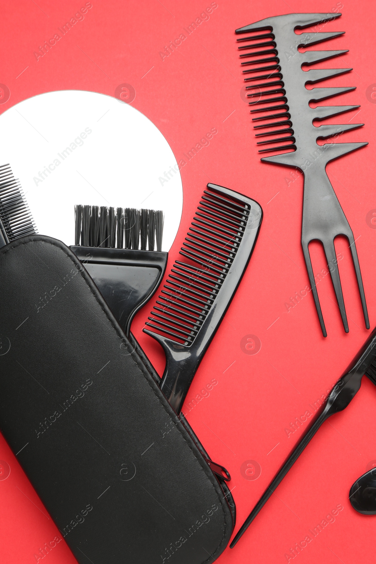 Photo of Different hairdresser's tools on red background, flat lay