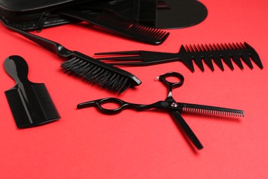 Photo of Different hairdresser's tools on red background, closeup