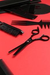 Photo of Different hairdresser's tools on red background, closeup