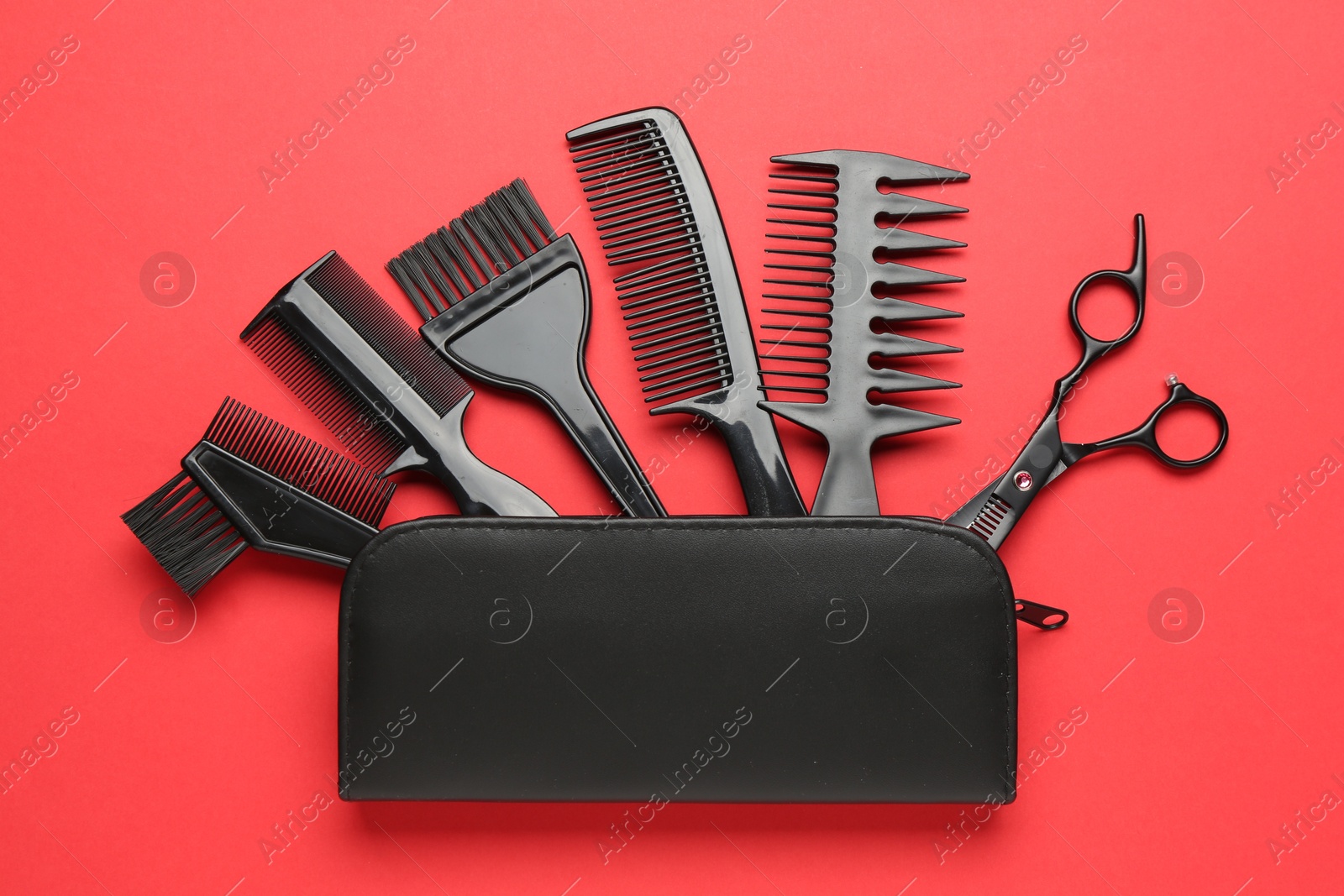 Photo of Different hairdresser's tools and case on red background, flat lay