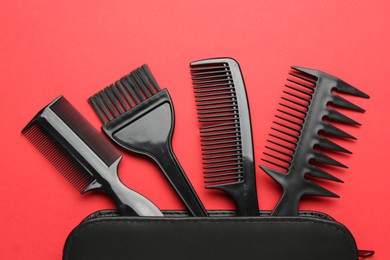 Photo of Different hairdresser's tools and case on red background, flat lay
