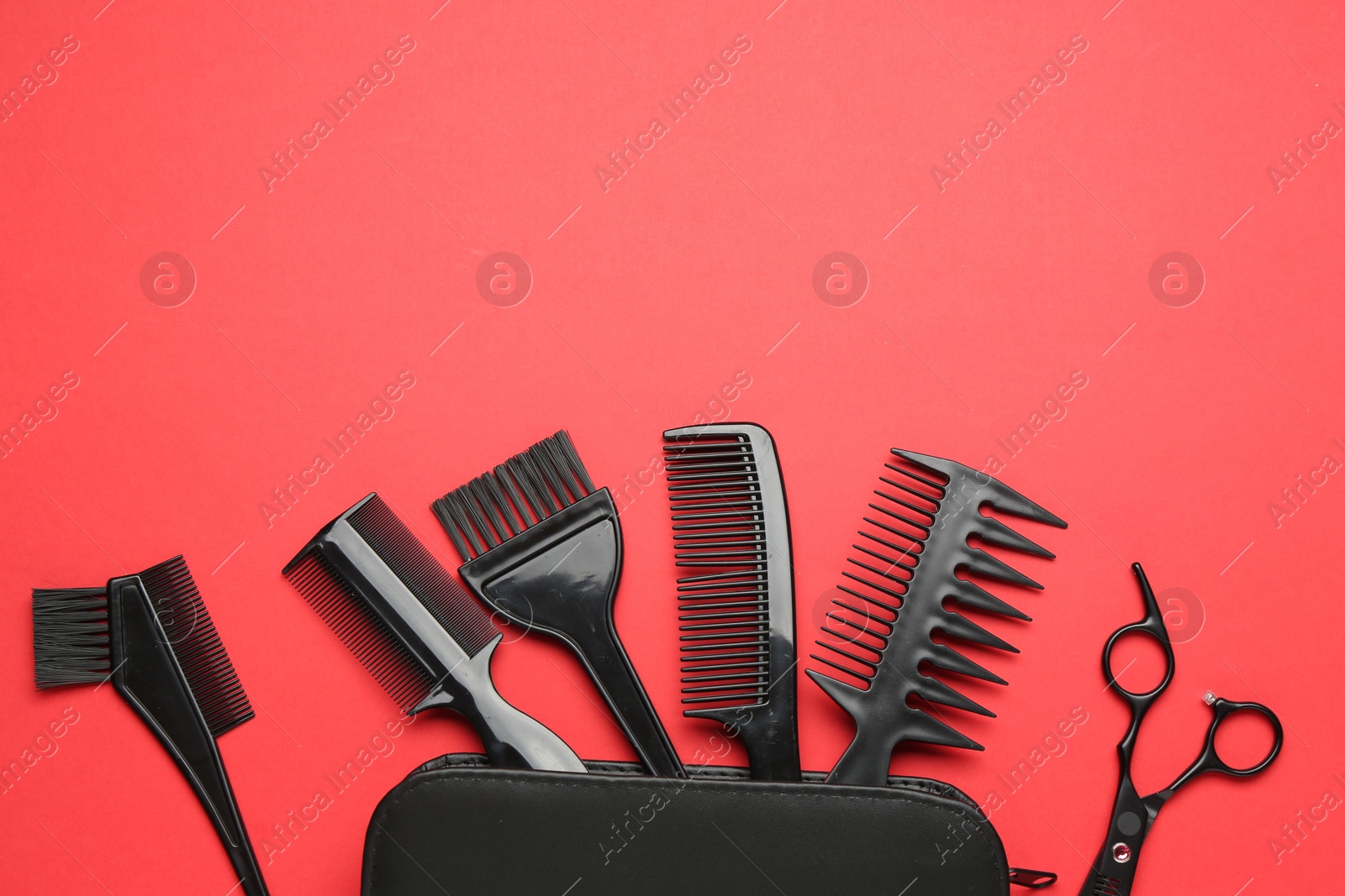 Photo of Different hairdresser's tools and case on red background, flat lay. Space for text