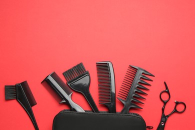 Photo of Different hairdresser's tools and case on red background, flat lay. Space for text