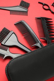 Photo of Different hairdresser's tools and case on red background, closeup