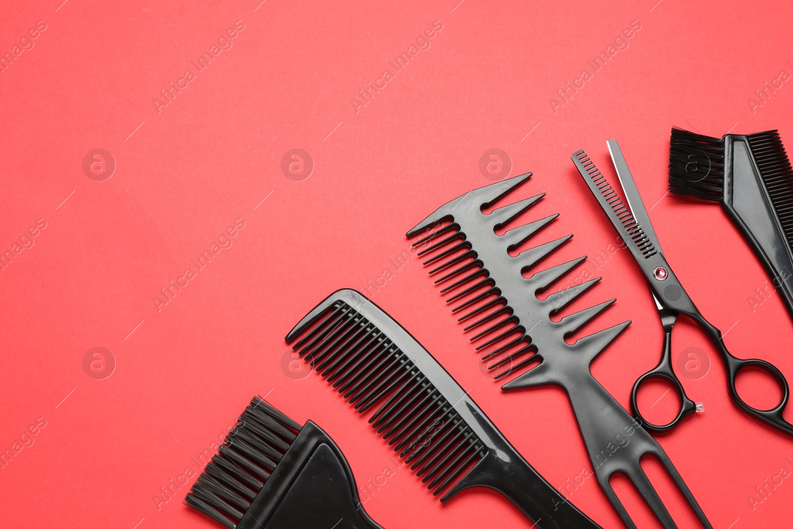 Photo of Different hairdresser's tools on red background, above view. Space for text