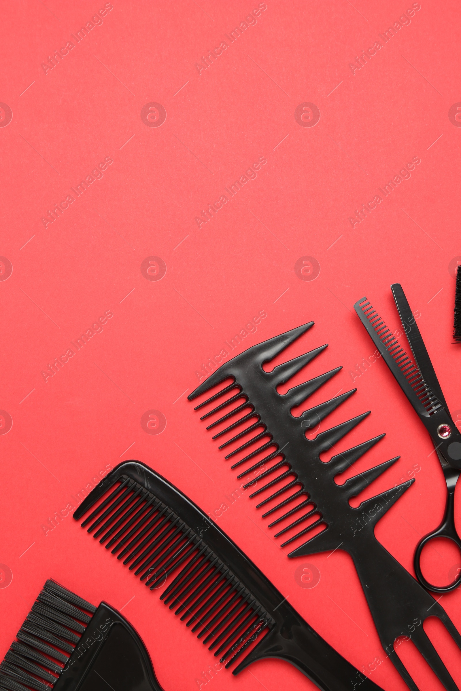 Photo of Different hairdresser's tools on red background, flat lay. Space for text