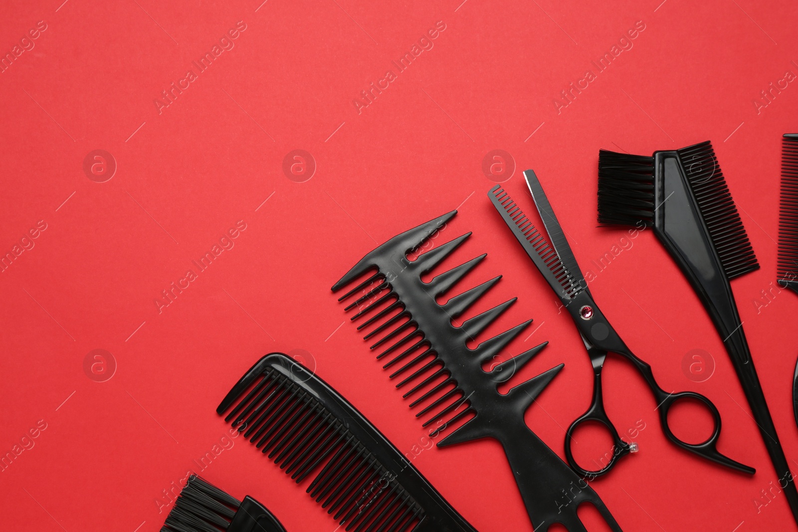 Photo of Different hairdresser's tools on red background, flat lay. Space for text