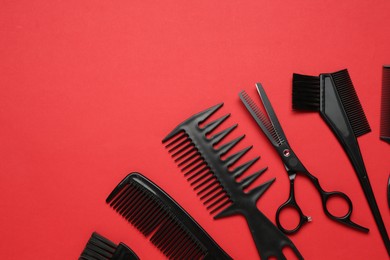 Photo of Different hairdresser's tools on red background, flat lay. Space for text