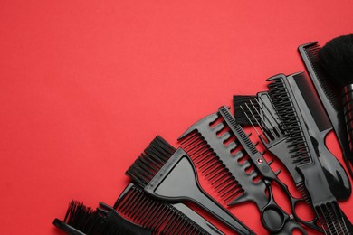 Photo of Different hairdresser's tools on red background, flat lay. Space for text