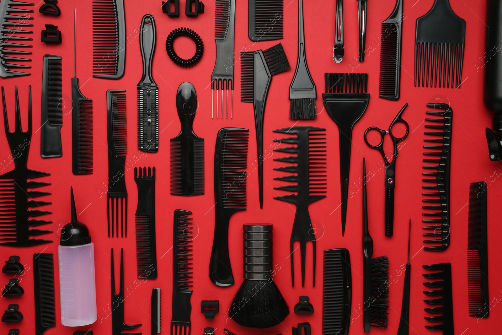 Photo of Different hairdresser's tools on red background, flat lay