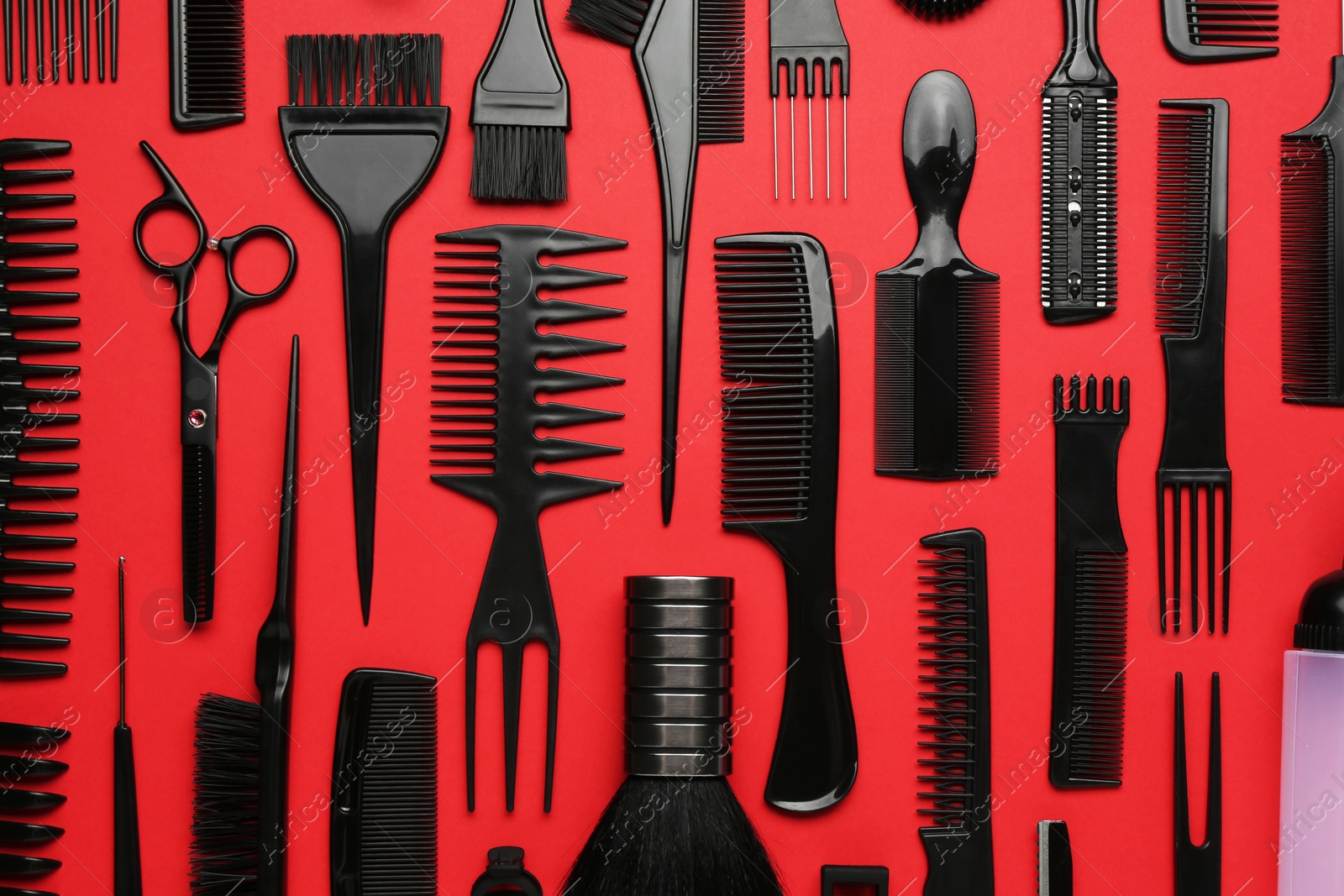 Photo of Different hairdresser's tools on red background, flat lay