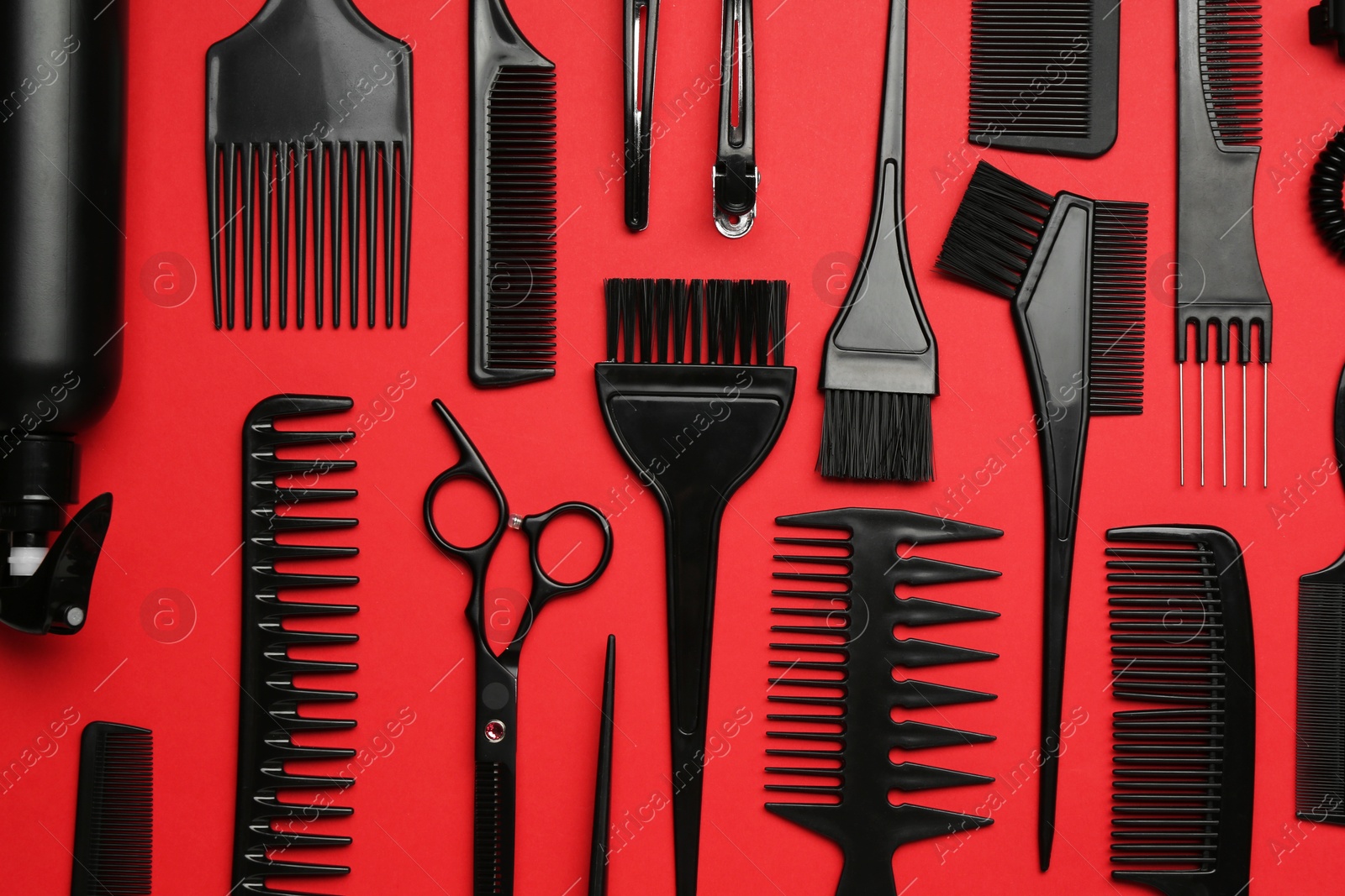 Photo of Different hairdresser's tools on red background, flat lay