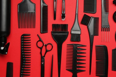Photo of Different hairdresser's tools on red background, flat lay
