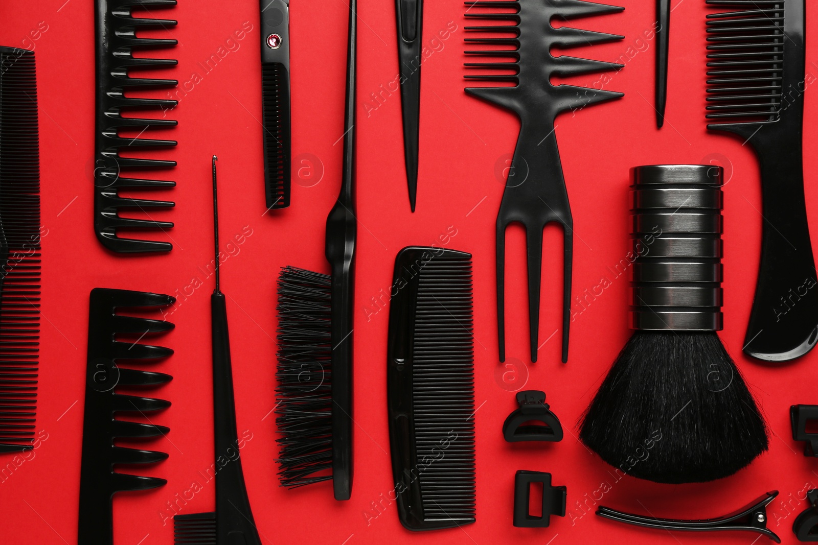 Photo of Different hairdresser's tools on red background, flat lay