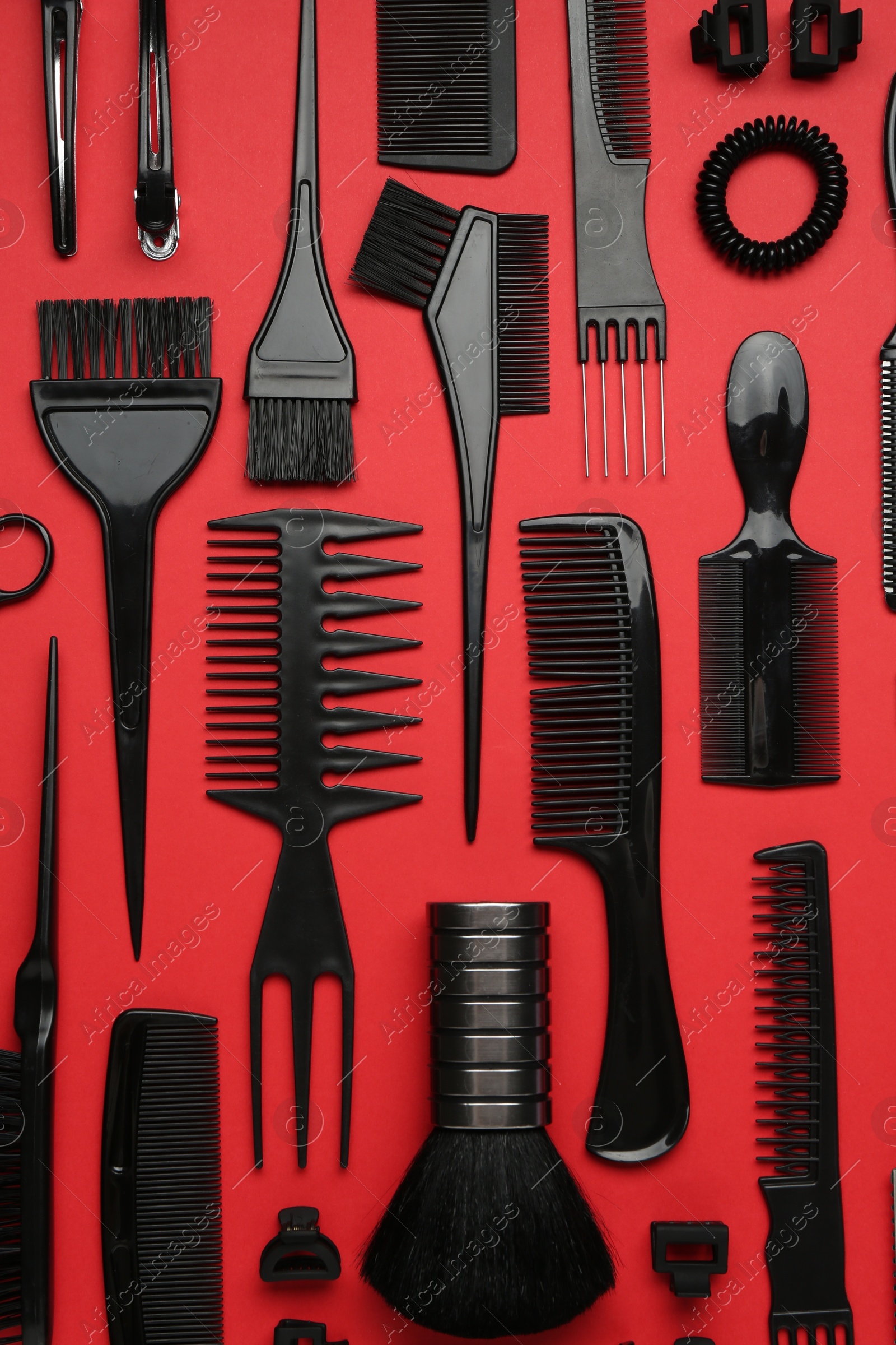 Photo of Different hairdresser's tools on red background, flat lay