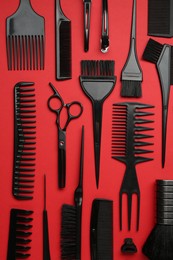 Photo of Different hairdresser's tools on red background, flat lay