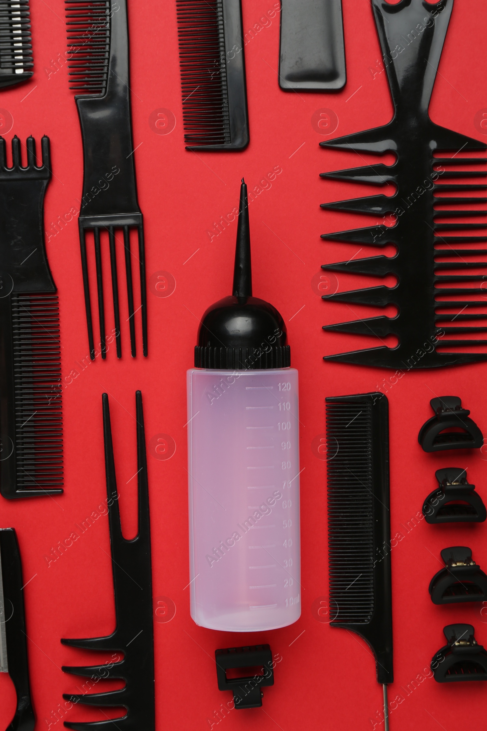 Photo of Different hairdresser's tools on red background, flat lay