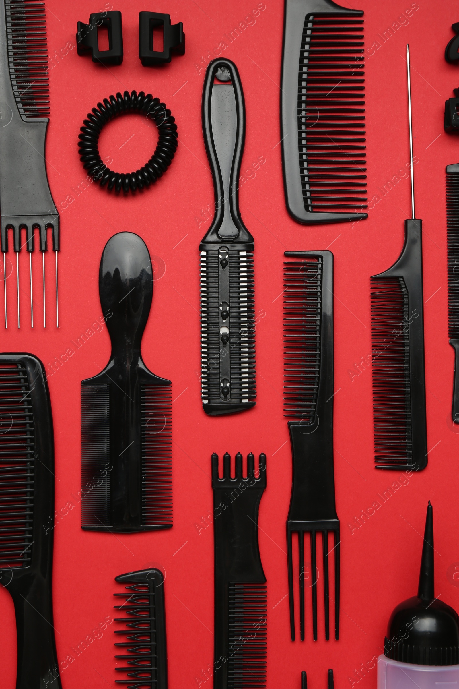 Photo of Different hairdresser's tools on red background, flat lay