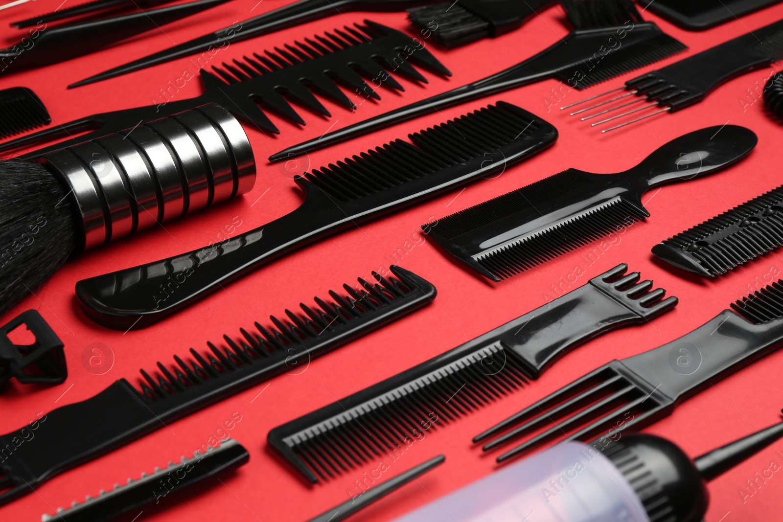Photo of Different hairdresser's tools on red background, closeup