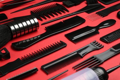 Photo of Different hairdresser's tools on red background, closeup
