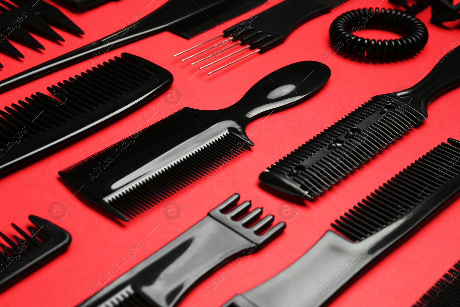 Photo of Different hairdresser's tools on red background, closeup