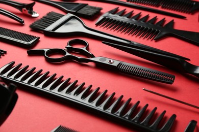 Photo of Different hairdresser's tools on red background, closeup