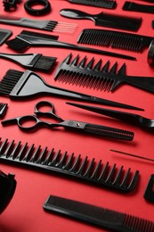 Photo of Different hairdresser's tools on red background, closeup