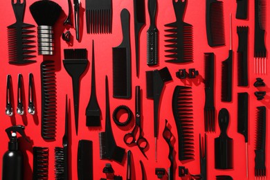 Photo of Different hairdresser's tools on red background, flat lay