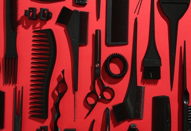 Photo of Different hairdresser's tools on red background, flat lay