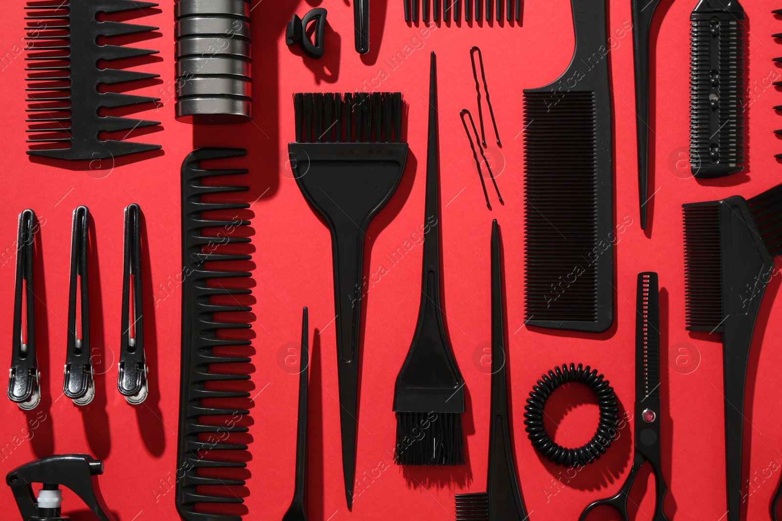 Photo of Different hairdresser's tools on red background, flat lay
