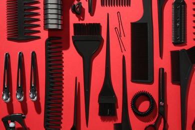 Photo of Different hairdresser's tools on red background, flat lay