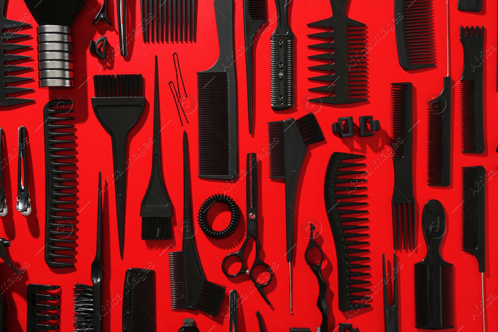 Photo of Different hairdresser's tools on red background, flat lay