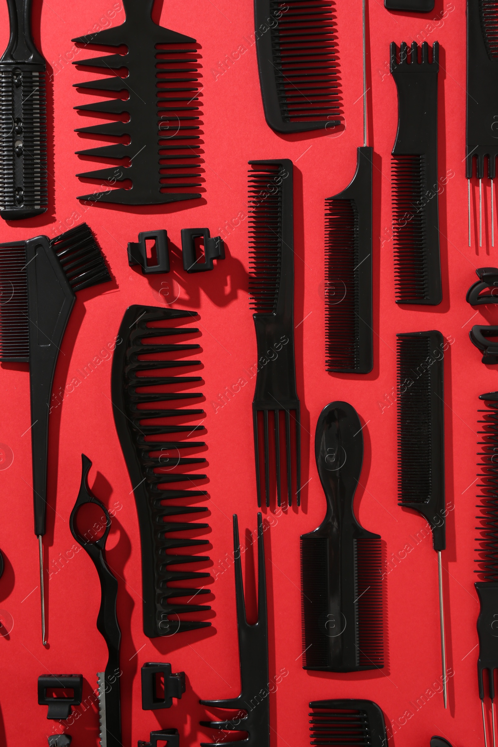 Photo of Different hairdresser's tools on red background, flat lay