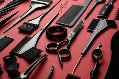 Photo of Different hairdresser's tools on red background, closeup