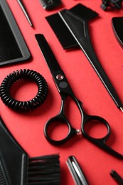Photo of Different hairdresser's tools on red background, closeup