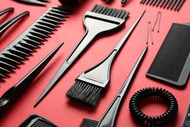 Photo of Different hairdresser's tools on red background, closeup