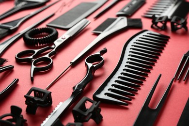Photo of Different hairdresser's tools on red background, closeup