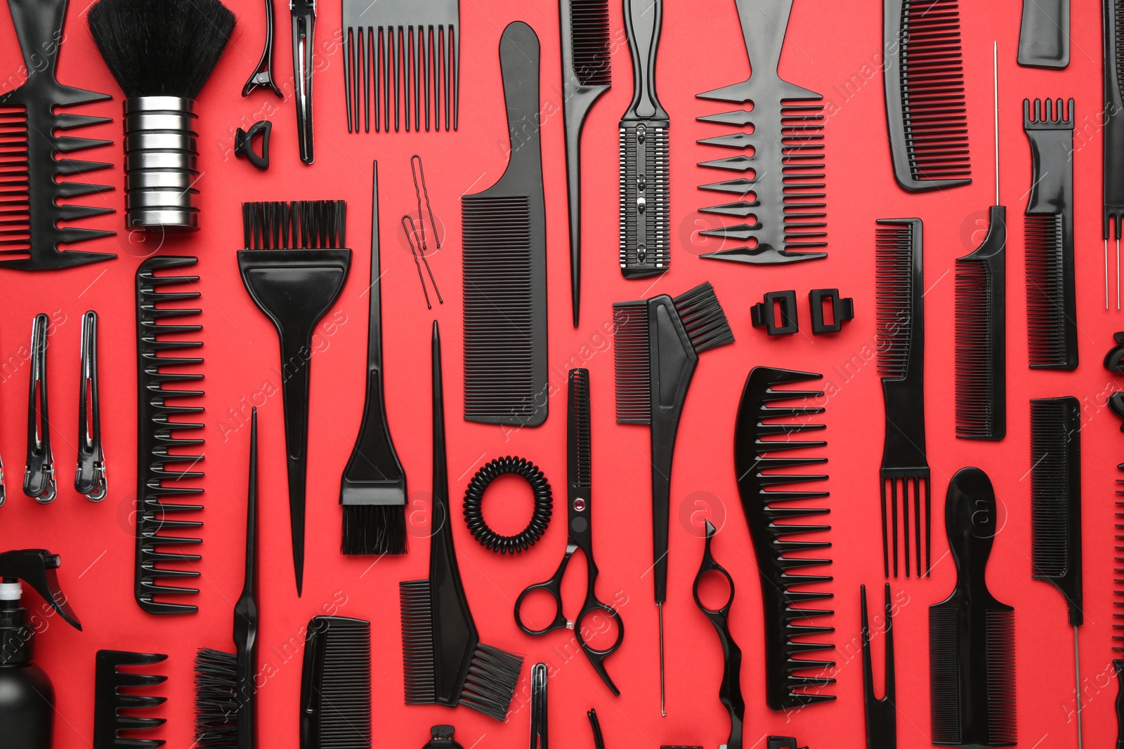 Photo of Different hairdresser's tools on red background, flat lay