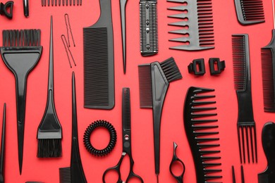 Photo of Different hairdresser's tools on red background, flat lay