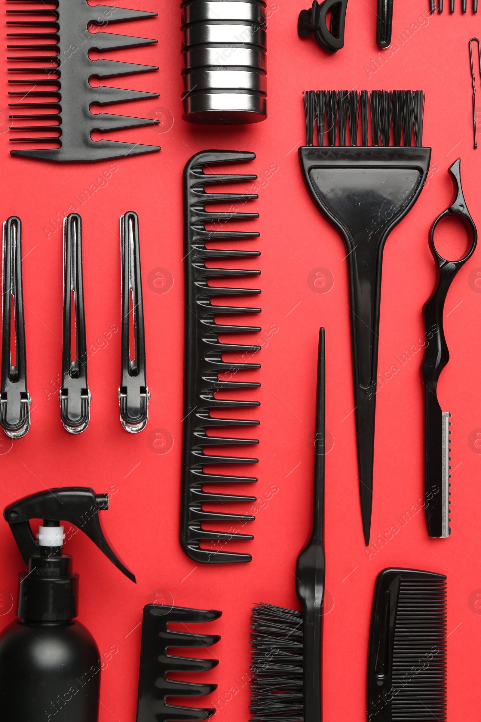 Photo of Different hairdresser's tools on red background, flat lay