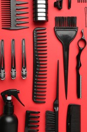Photo of Different hairdresser's tools on red background, flat lay