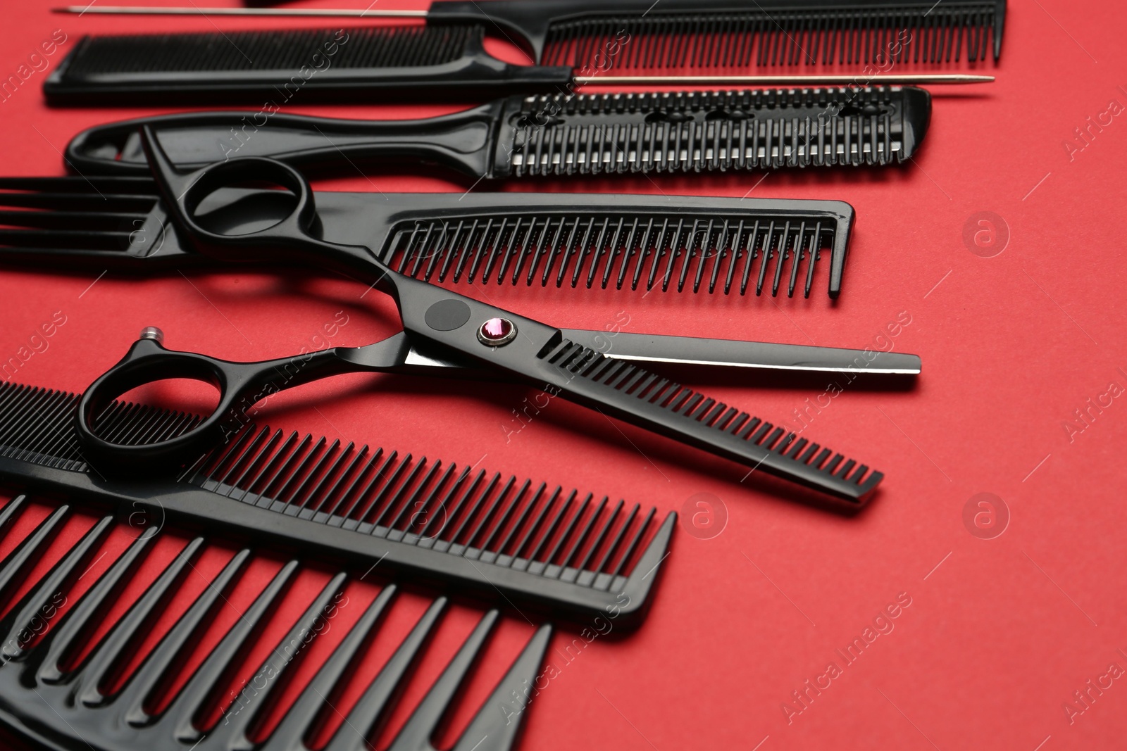 Photo of Different hairdresser's tools on red background, closeup