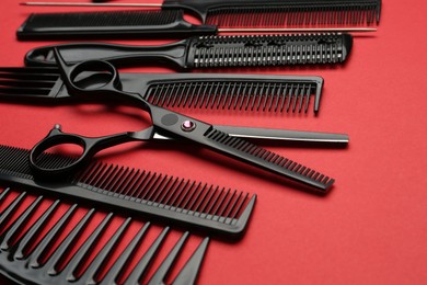 Photo of Different hairdresser's tools on red background, closeup