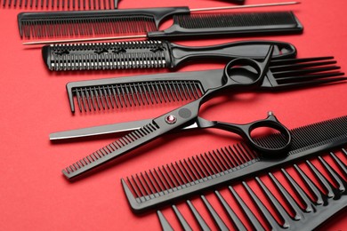 Photo of Different hairdresser's tools on red background, closeup