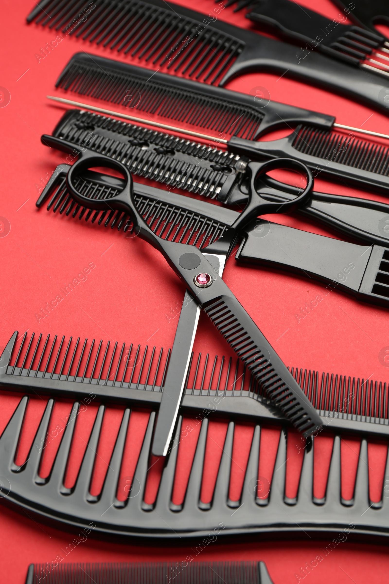 Photo of Different hairdresser's tools on red background, closeup