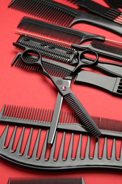 Photo of Different hairdresser's tools on red background, closeup