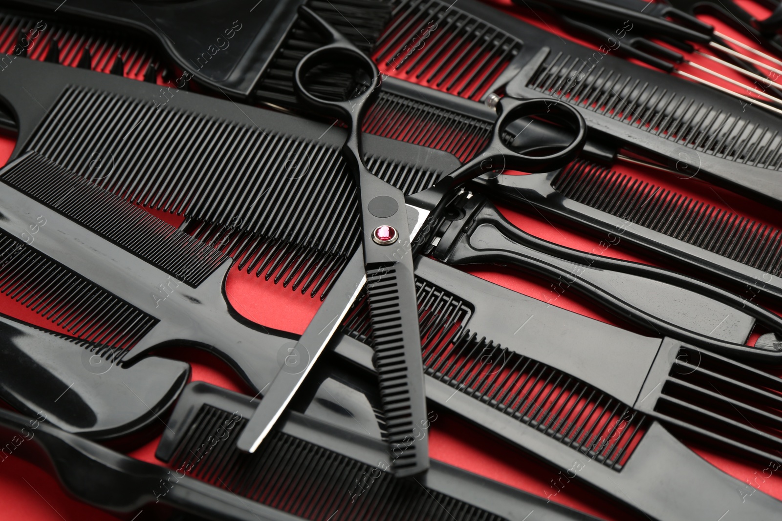 Photo of Different hairdresser's tools on red background, closeup